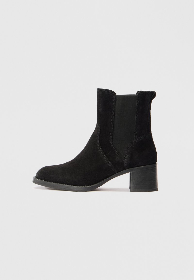 Stivaletti neri in suede con punta tonda, pannelli laterali elasticizzati e tacco a blocco texturizzato. Finitura liscia con dettagli di cucitura sottili.