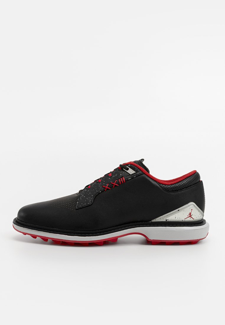 Chaussure de golf noire avec des accents rouges, dotée d'un dessus en cuir lisse, de détails en maille et d'une semelle extérieure moulée avec une adhérence texturée.