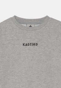 Felpa grigia con scollatura rotonda e finitura testurizzata. Presenta la parola "KAOTIKO" ricamata in nero nella parte centrale del petto.