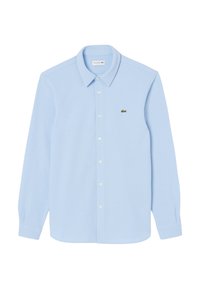 Camicia a maniche lunghe azzurro chiaro realizzata in materiale morbido. Presenta un colletto a punta, chiusura con bottoni sul davanti e un piccolo logo verde di Lacoste sul petto.