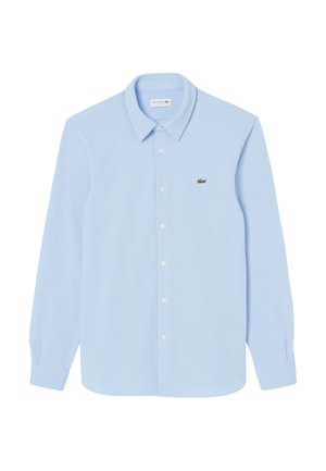 Light blue long-sleeve shirt made of soft material. Features a pointed collar, button-up front, and a small green Lacoste logo on the chest.