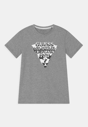Grå T-shirt med korte ærmer med en hvid og sort trekantet grafik med teksten "GUESS Los Angeles California 1981" og et spørgsmålstegn.