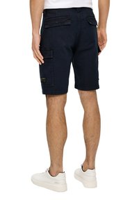 Navy cargo szorty wykonane z trwałego materiału, z wieloma kieszeniami, luźnym krojem i prostym dołem. Noszone z białymi trampkami.