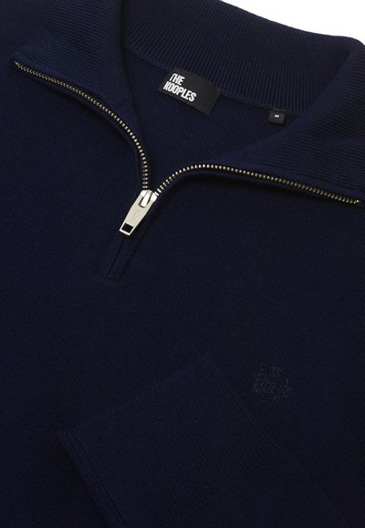 Granatowy sweter z półzamkiem, prążkowaną teksturą i małym detalem logo na rękawie. Wykonany z miękkiego materiału dzianinowego.