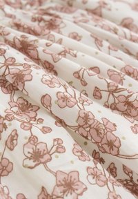 Letvægtsstof med et blomstermønster med pink blomster og grønne accenter på en hvid baggrund, med blød drapering og tekstur.