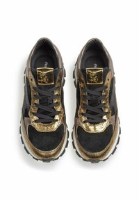 Czarno-złote sneakersy charakteryzują się połączeniem zamszowych i metalicznych tekstur, mają grubą podeszwę oraz wyraźny złoty detal na języku.