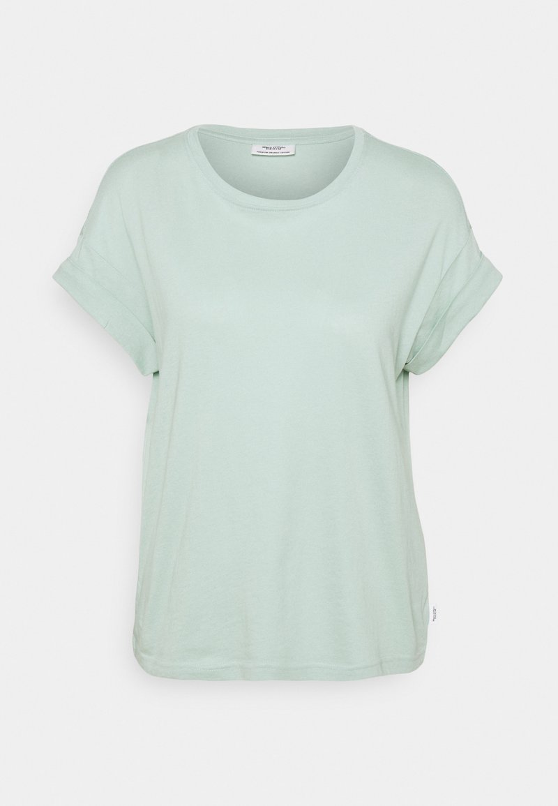 T-shirt en coton vert clair avec un col rond et des manches courtes retroussées. Texture douce et coupe décontractée, avec une petite étiquette sur l'ourlet.