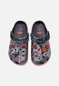 Μαύρα και γκρι Crocs με θέμα το Star Wars με κόκκινες λεπτομέρειες, διακοσμημένα με σύμβολα των Άρχοντα Σιθ και μπρελόκ χαρακτήρων σε απλό φόντο.