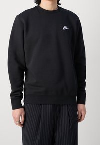 Černá mikina s kulatým výstřihem a dlouhými rukávy. Na hrudi je malé bílé logo Nike. Vyrobena z měkké tkaniny s hladkou strukturou.