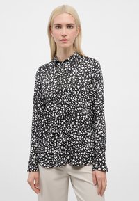 Overhemd met knopen, gemaakt van lichtgewicht stof, met een zwart-wit bloemmotief. Het heeft een kraag en lange mouwen met rechte manchetten.