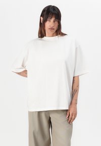 Witte oversized t-shirt van zachte katoen, ronde hals, korte mouwen en een relaxed fit, gecombineerd met lichtbeige wijde broek.
