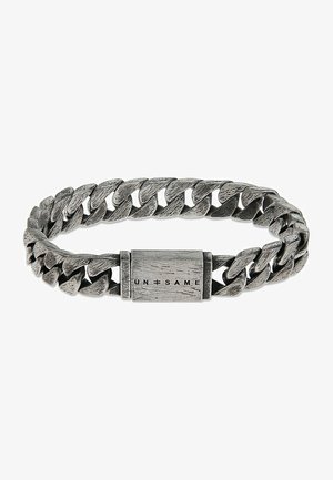 Bracelet en métal argenté présentant un design de chaîne tressée, une surface texturée et un fermoir rectangulaire avec l'inscription "UN=SAME" gravée.