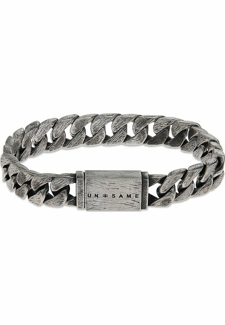 Silverfärgad metallarmband med ett vävt kedjemönster, en texturerad yta och ett rektangulärt spänne med "UN=SAME" ingraverat.