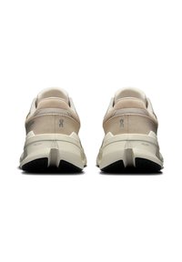 Beige és krém színű sportcipők párja, vastag talppal, hátulról, fehér háttéren bemutatva.