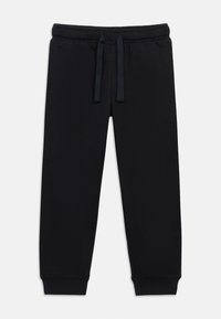 Črne trenirke iz mehkega bombažnega mešanega materiala z elastičnim pasom in vrvico za zategovanje, zoženimi hlačnicami in rebrastimi manšetami. Brez vidnih logotipov ali vzorcev.