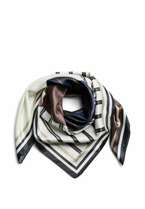 Femme aux cheveux bouclés foncés portant un haut gris clair à manches longues avec des coutures noires et un foulard rayé noir, blanc et beige autour du cou.