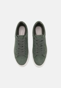Green suede sneakers with round toe, lace-up front, and textured laces. Features a white rubber sole and a padded collar.