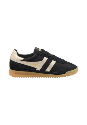 Zwarte lage sneaker met beige strepen, beige hieldetail, rubberen zool en zwarte veters, gezien van opzij op een witte achtergrond.