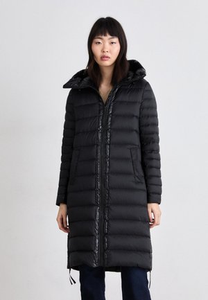 Schwarze Steppjacke mit Kapuze, ausgestattet mit einem Reißverschluss, gestepptem Muster und seitlichen Taschen. Die Länge reicht bis zur Mitte des Oberschenkels und hat verstellbare Kordeln.