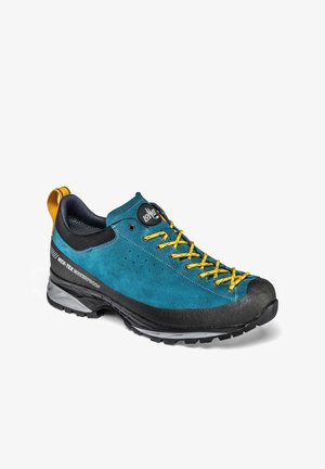 Zapato de senderismo azul con cordones amarillos, suela negra, etiqueta impermeable MER-TEX y lazo amarillo en el talón sobre fondo blanco.