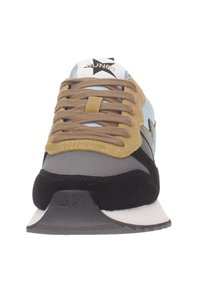Zapatilla con parte superior de tela azul claro, acentos de ante negro, cordones marrones, paneles grises y una suela texturizada con detalles del logo.