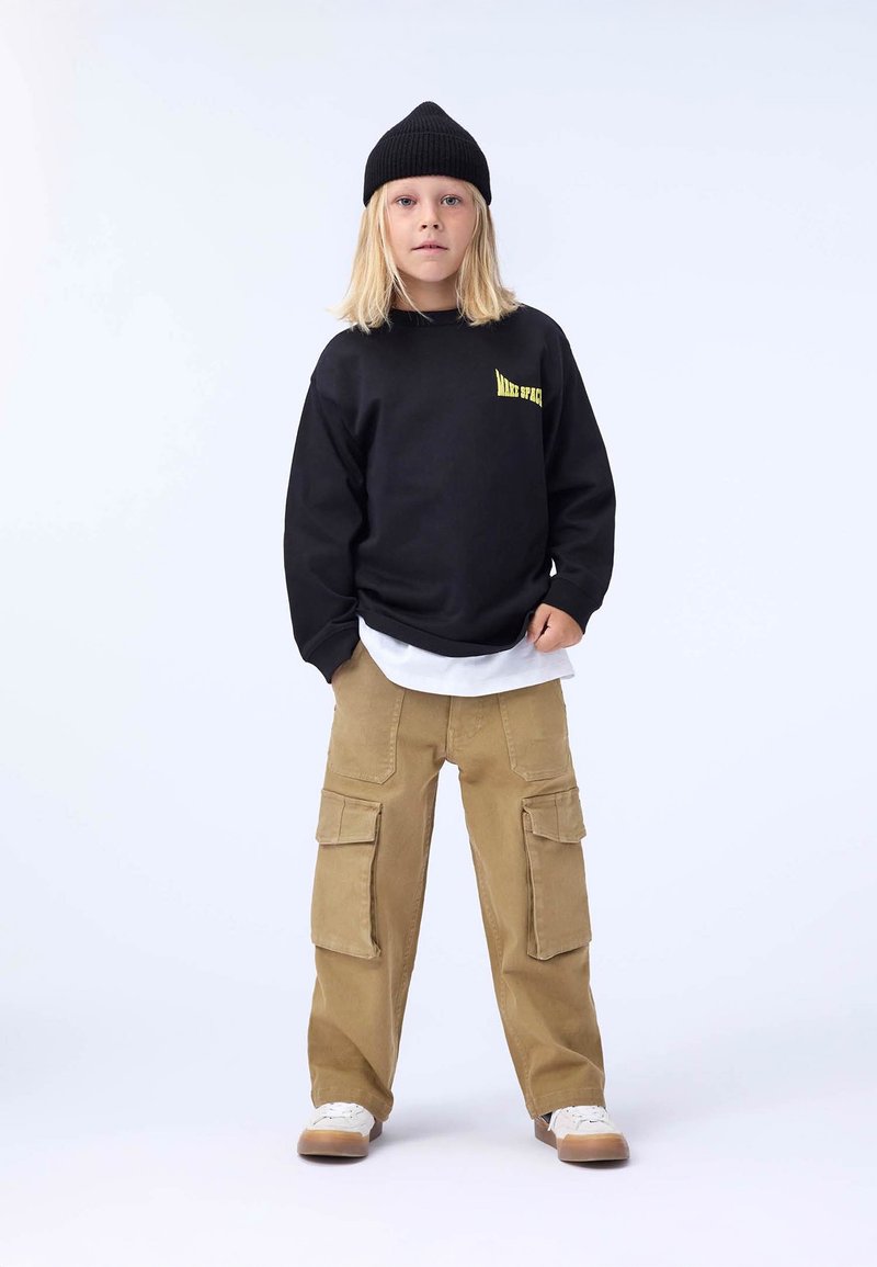 Black sweatshirt with "Mars Space" logo, layered over a white shirt; khaki cargo pants with large pockets; black knit beanie; white sneakers.
