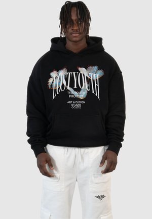 Black hoodie with a graphic print of colorful butterfly wings and text. Features a kangaroo pocket and a relaxed fit. Worn with white cargo shorts.
