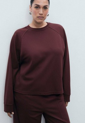 Felpa borgogna con scollo rotondo e maniche raglan, realizzata in un tessuto morbido. Presenta polsini a costine e una vestibilità comoda.