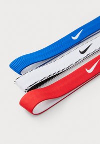 Ensemble de trois élastiques à cheveux : bleu, rouge et blanc. Chacun avec une texture distinctive et des coutures noires contrastantes, arborant le logo Nike.