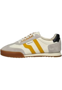 Sneakers con parte superiore in pelle color crema, dettagli in suede grigio e strisce gialle. Suola in gomma, punta rotonda e lacci bianchi. Logo GANT presente.
