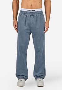 Φόρμας σε ανοιχτό μπλε χρώμα από μαλακό ύφασμα, με ελαστική μέση που φέρει μαύρο λογότυπο "PEGADOR". Χαλαρή εφαρμογή και με μανσέτες στους αστραγάλους.