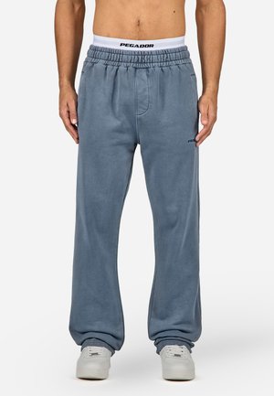 Hellblaue Jogginghose aus weichem Stoff, mit elastischem Bund und schwarzem "PEGADOR"-Logo. Lockerer Schnitt und mit Bündchen an den Knöcheln.