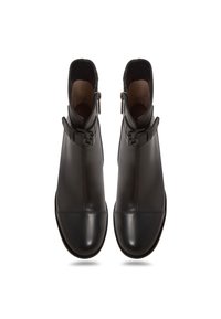 Botas de tobillo de cuero negro con puntera brillante, cremallera lateral y una correa decorativa con hebilla en cada bota. Textura suave y diseño elegante.