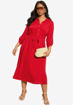 Red midi dress with a button-down front, elastic waist, 3/4 sleeves, and a cinched design; paired with a woven clutch and strappy sandals.