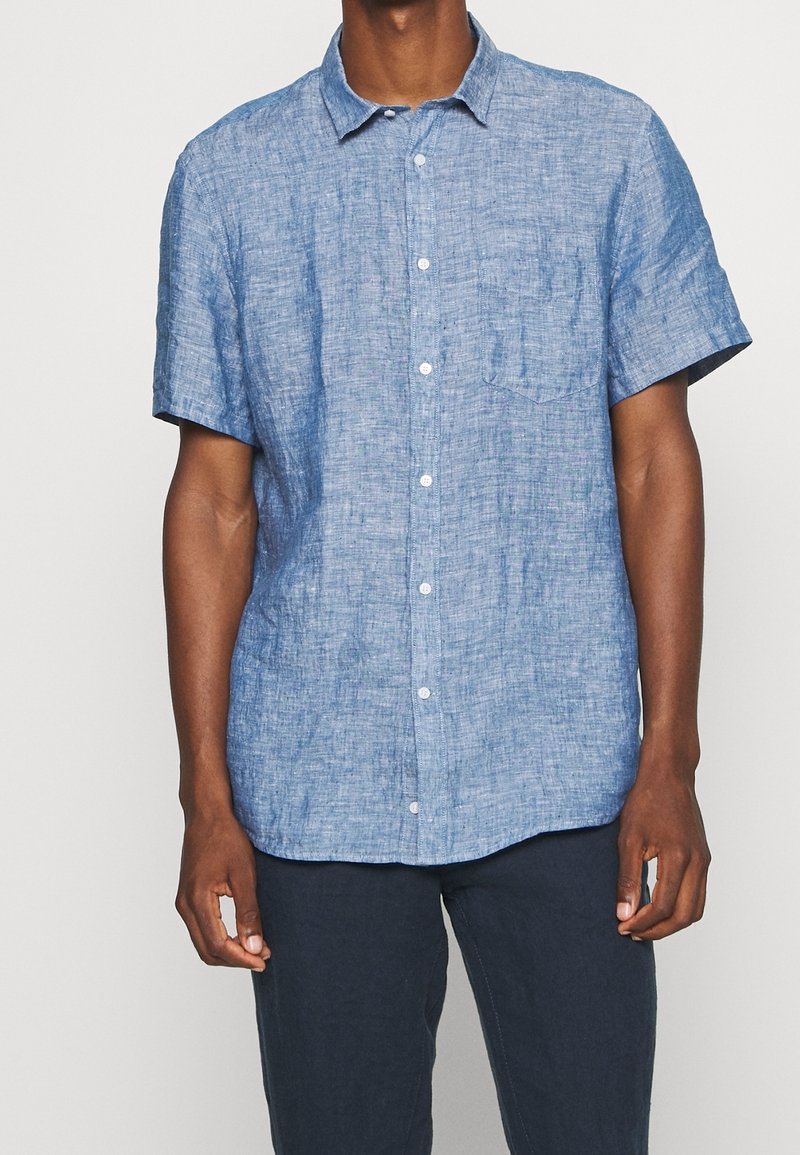 Camicia a maniche corte in lino azzurro chiaro, con design a bottoni, colletto e taschino sul petto. Tessuto strutturato con una trama sottile.