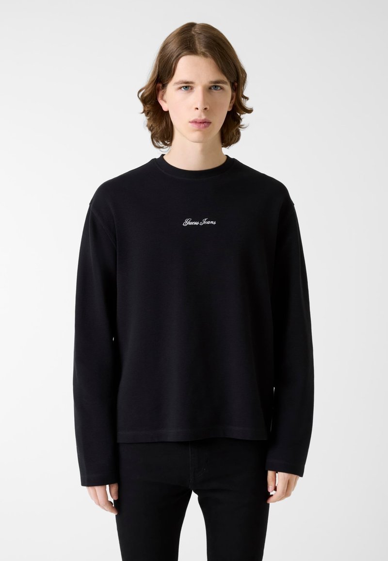 Czarna bluza z długim rękawem i okrągłym dekoltem, z białym haftowanym logo "Gius Jeans" na piersi. Wykonana z fakturowanej tkaniny.