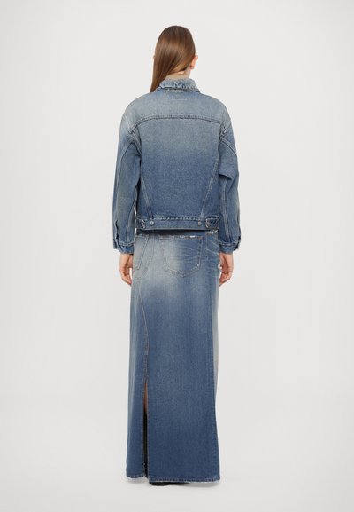 Denim jacket with long, flared denim skirt. Both are light blue with a slightly faded texture and side slit, featuring metallic buttons.