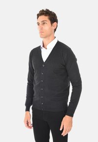 Cardigan nero da uomo con scollo a V, chiusura frontale con bottoni e maniche lunghe. Realizzato in materiale morbido con una superficie liscia e polsini a coste.