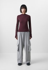 Burgundy långärmad tröja med hög hals; grå cargo-byxor med sidofickor; avslappnad passform; bomullsblandning; sportig estetik.