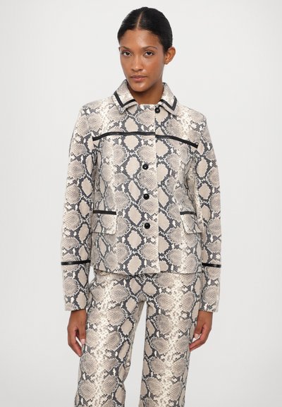 Blazer con estampado de piel de serpiente en beige y negro, que presenta un cuello, cierre de botón y dos bolsillos frontales con acentos en negro. Tejido texturizado.