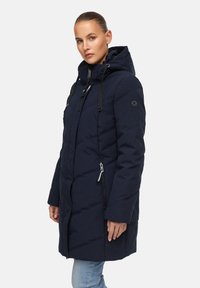Marineblauwe gewatteerde jas met een capuchon, voorzien van een diagonale quiltpatroon, ritszakken en zwarte trekkoorden op de capuchon.