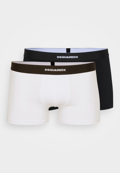 Zwei Paare Boxershorts: eine schwarze mit schwarzem Bund, eine weiße mit braunem Bund, beide mit dem DSQUARED2-Logo auf den Bünden.
