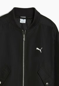 Veste noire Puma avec fermeture éclair intégrale à l'avant, col côtelé, poches inclinées avec boutons-pression et logo Puma blanc sur la poitrine gauche.