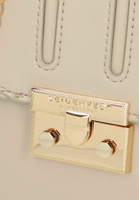 Borsa a tracolla in pelle color crema con chiusura dorata e marchio inciso. Include dettagli con cuciture verticali e accenti di hardware decorativo.