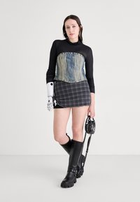 Džínová korzetová halenka, černá dlouhá košile, kostkovaná mini sukně, černé kozačky do kolen, stříbrné akcenty, kovová protéza na ruku, černá kabelka.