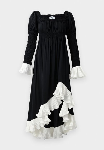 Juoda suknelė su ilgomis, raukinėtomis rankovėmis, kvadratiniu iškirpimu ir baltomis raukinėmis puošmenomis ant manžetų ir apvado, sukurianti laisvą siluetą.