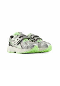 Silver athletic shoes with green accents and textured mesh upper. Features a dual hook-and-loop strap and rubber sole for grip.