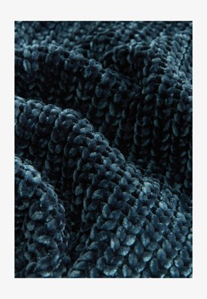 Weicher, plüschiger türkisfarbener Samtstoff mit einer dicken, strukturierten Oberfläche und einem abgerundeten, gesteppten Muster, das ein reichhaltiges haptisches Erscheinungsbild erzeugt.