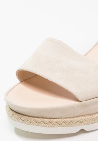 Sandale beige à enfiler avec large bride en suédine, semelle intérieure rembourrée, semelle intermédiaire en jute tressée et semelle extérieure en caoutchouc blanc.