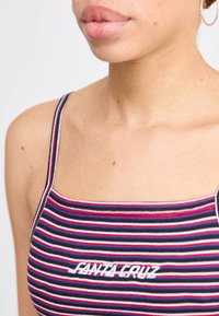 Camisola sem mangas com riscas multicoloridas em azul, vermelho e branco. Apresenta o logótipo "Fanta Cruz" em costura branca na parte da frente.
